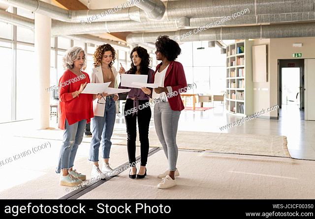 Businesswoman discussing over documents with colleagues in office