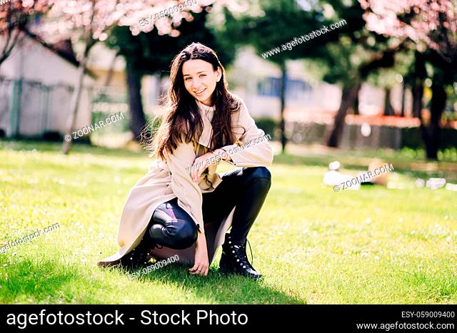 lifestyle fashion portrait of young happy woman outdoors. Fashion concept of female wearing champagne coat. Minimalistic and light female portrait
