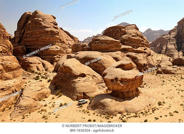 Off-road vehicle driving between rocks in the desert, Wadi Rum, Hashemite Kingdom of Jordan, Middle East, Asia