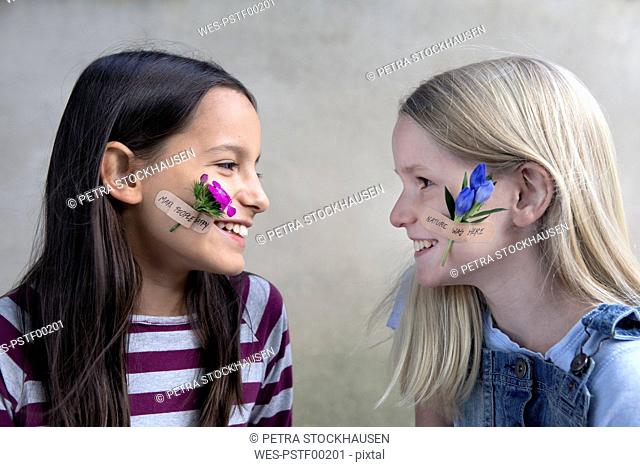 Two smiling girls with flower heads on their cheeks