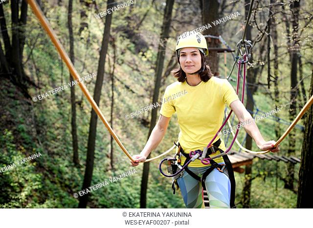 Young woman wearing yellow t-shirt and helmet in a rope course