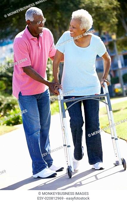 Senior Man Helping Wife With Walking Frame