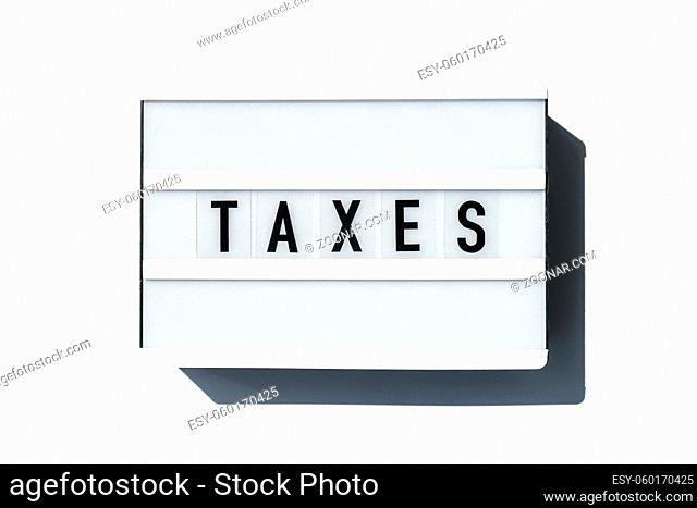 Lightbox board on a white background with the words TAXES in black letters. Currency, cash