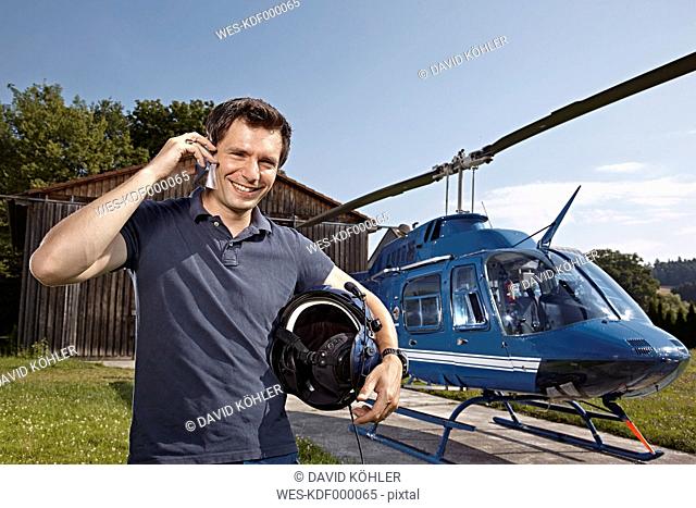 Germany, Bavaria, Landshut, Helicopter pilot using mobile phone