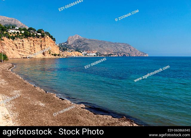 Tranquil stone beach with turquoise colored ocean with view on rocky cliffs, Altea, Costa Blanca, Spain
