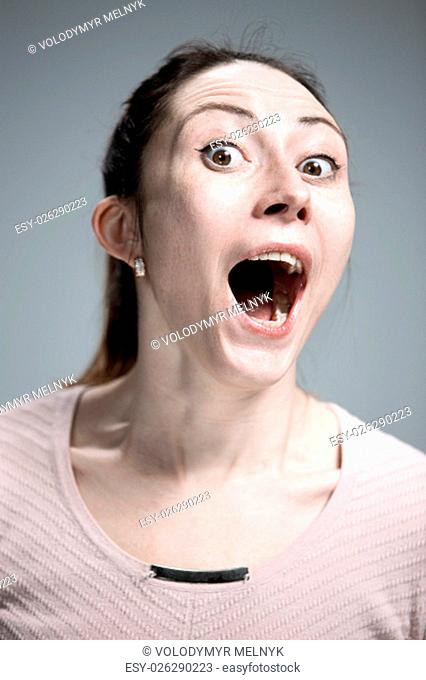 Portrait of young woman with shocked and surprised facial expressions over gray background