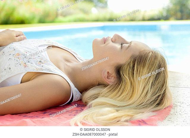 Woman relaxing by pool with eyes closed