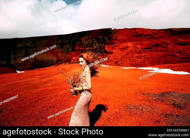 Portrait of a model bride in a gold wedding evening dress, in a yellow-red sandy quarry, in the crater of a volcano in Iceland, Golden Circle