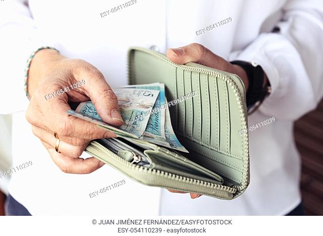Close up of hand of woman taking out pounds from her purse