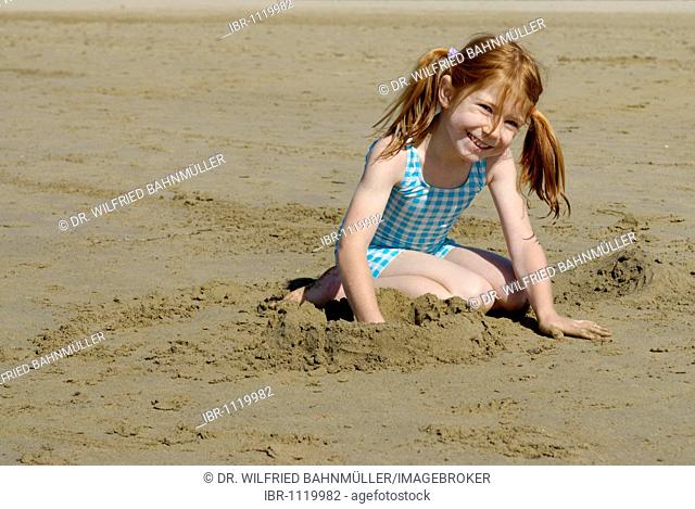 Girl lying and playing on the beach, seaside of the Adria, Bibione, Venetia, Venice, Italy, Europe