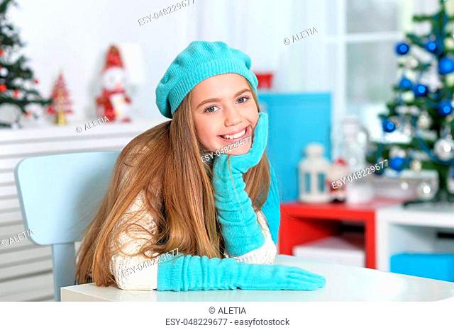 Portrait of smiling in blue beret, scarf and gloves looking at the camre
