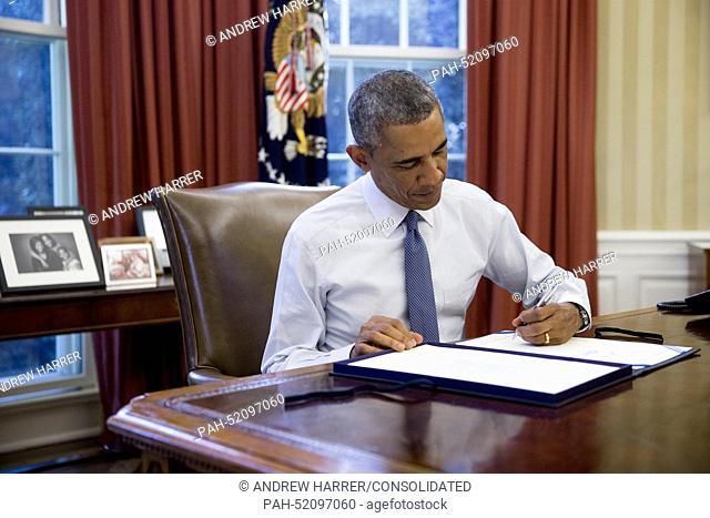 United States President Barack Obama signs House Joint Resolution 124, the Continuing Appropriations Resolution, 2015, in the Oval Office of the White House in...