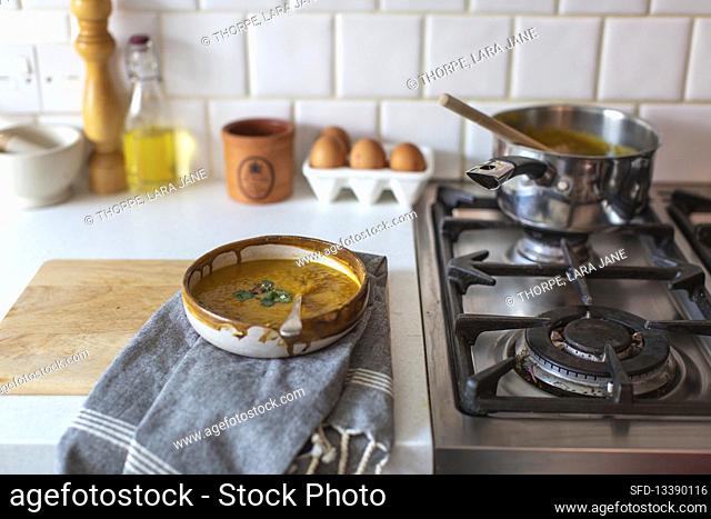 Cream soup in a ceramic bowl next to a gas stove in a country kitchen