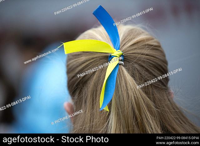 22 April 2022, North Rhine-Westphalia, Bonn: A participant has knotted a bow in the colors of the Ukrainian flag in her hair