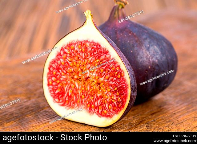 One whole and on half sliced ripe, delicious and sweets figs on a old rustic wooden cutting board