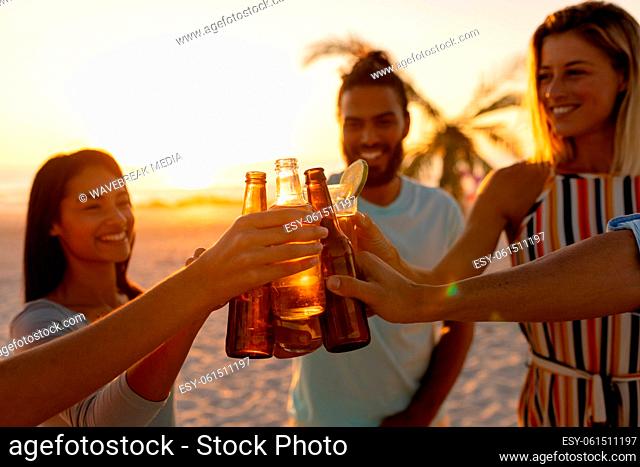 Mixed race friends drinking beer on beach