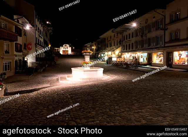 Gruyeres, VD / Switzerland - 31 May 2019: the historic medieval village of Gruyeres with the village square fountain at night