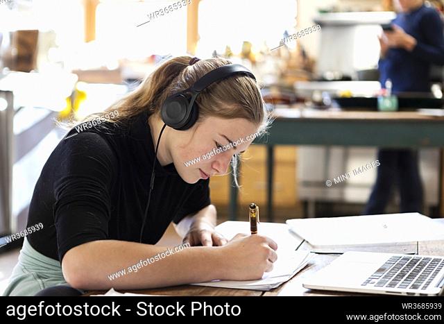 teenage girl wearing headphones, drawing on paper