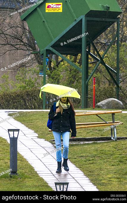 Stockholm, Sweden A woman walking with an umbrella in the Kungshamra student housing neighbourhood in the Solna suburb