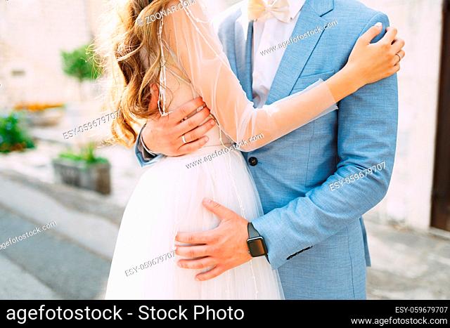 The bride and groom are tenderly embracing on the street of the old town of Perast, close-up. High quality photo