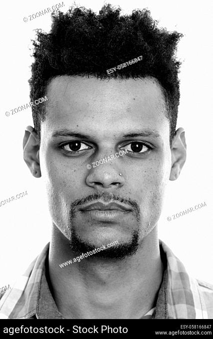 Studio shot of young bearded African businessman with afro hair isolated against white background in black and white