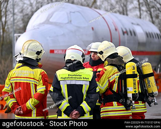 29 March 2022, Thuringia, Erfurt: Firefighters discuss the training task in front of a fire simulator at Erfurt-Weimar Airport