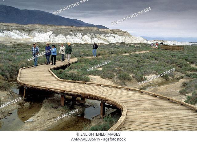 Tourists walking on wooden boardwalk nature trail path at Salt Creek, Death Valley National Park, California