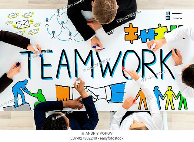 High Angle View Of Businesspeople Drawing Teamwork Concept On Office Desk With Colorful Marker