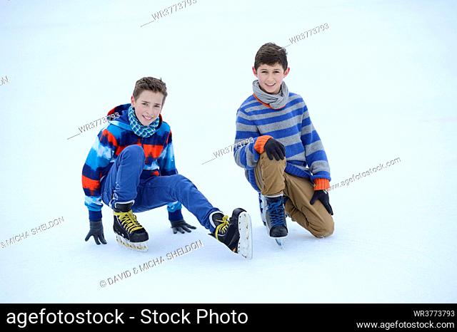 Two boys with ice-skates on a frozen lake
