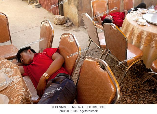 Caterering staff fall asleep before a buddhist wedding in a small village outside of Phnom Penh, Cambodia