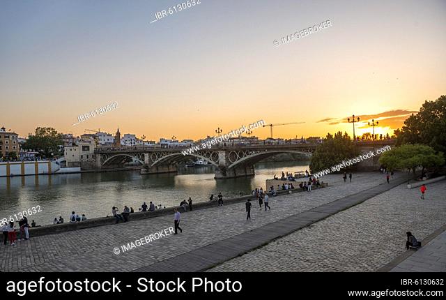 Waterfront Muelle de la sal at the river Rio Guadalquivir with bridge Puente de Triana, sunset, Sevilla, Andalusia, Spain, Europe