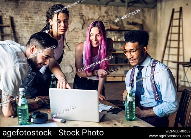 Creative team having business meeting in loft office using laptop