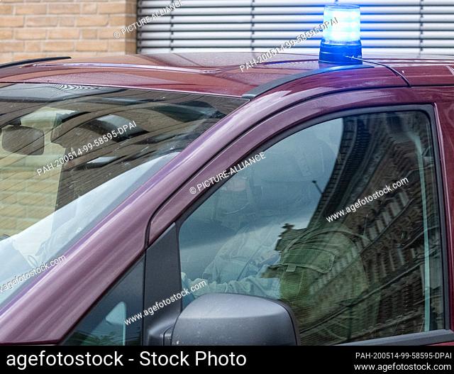 14 May 2020, Saxony, Dresden: Police officers drive in a column out of the inner courtyard of the Dresden Justice Center, which is reflected in the car window