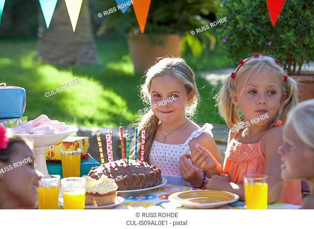 Girl sitting at table with birthday cake