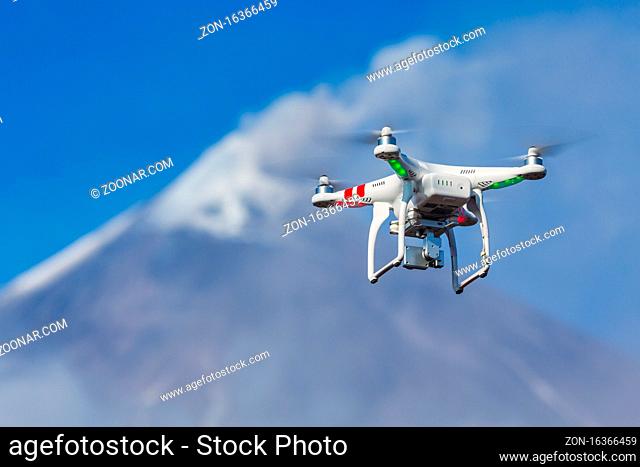 Flying drone quadcopter UAV aerial photography in sky on background volcano eruption, mount peak erupting ashes, gas from active crater