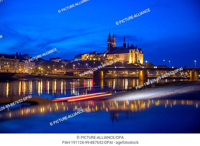 15 October 2019, Saxony, Meißen: The illuminated Albrechtsburg Castle and the cathedral of Meissen are reflected in the evening in the Elbe