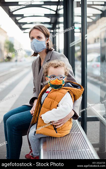 Mother and son with mask waiting for the bus