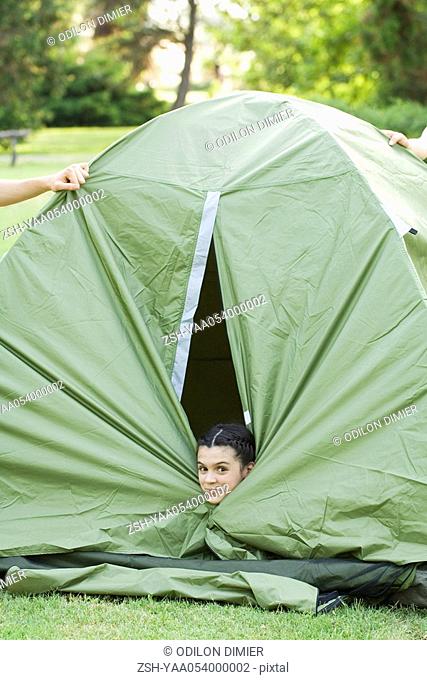 Young camper peeking head out of tent