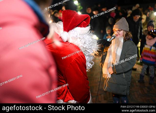 17 December 2023, Lower Saxony, Greetsiel: After arriving on the fishing boat, Santa Claus goes ashore and is greeted by children