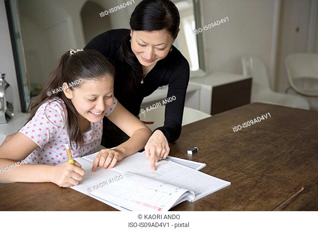 Mother helping teenage daughter with homework