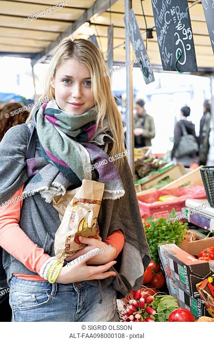 Young woman at greengrocer's buying fresh fruits and vegetables