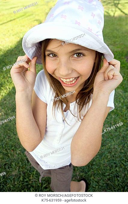 Smiling girl with hands pulling on her hat