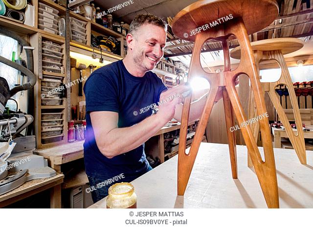 Craftsman polishing wooden stool with oil finish