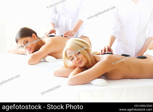 Pretty female friends getting hot stone massage together in the health spa
