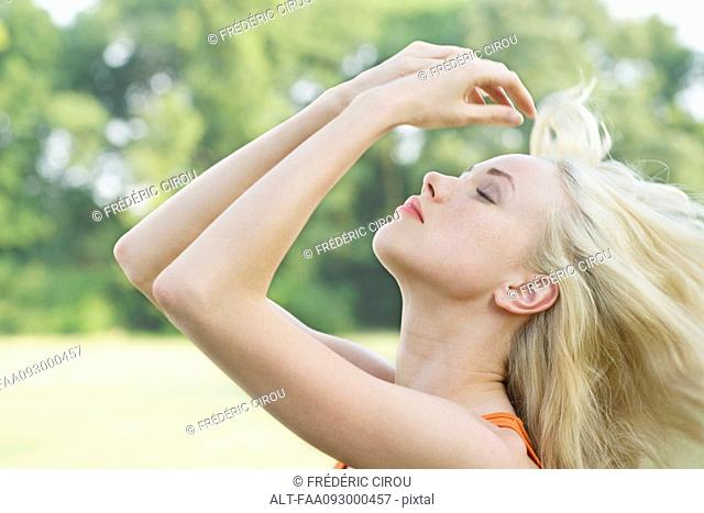 Young woman tossing her hair outdoors, portrait