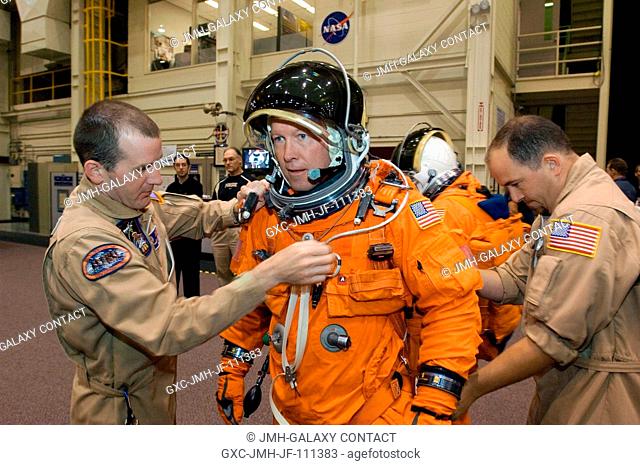 Astronaut Dominic L. Gorie, STS-123 commander, gets help donning a training version of his shuttle launch and entry suit in preparation for an emergency egress...