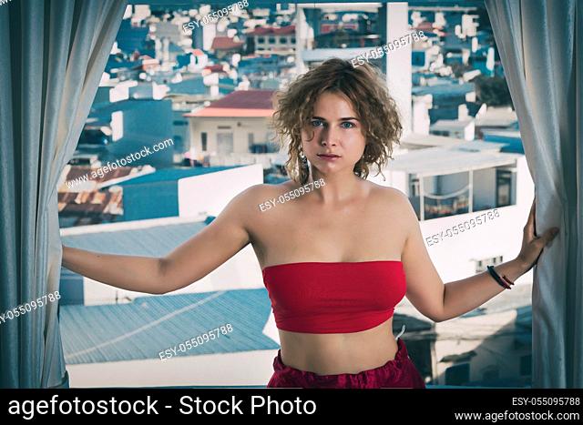 Fashion style portrait of a beautiful woman in red on a balcony