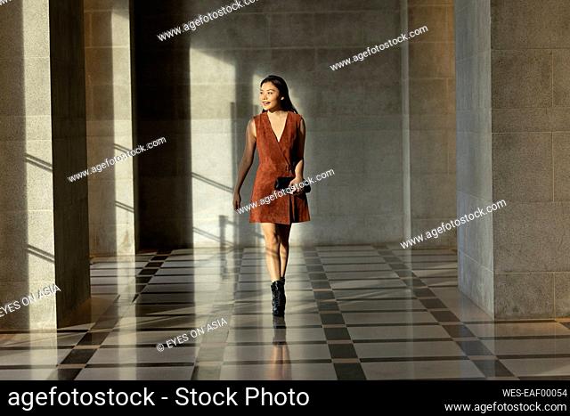 Smiling woman looking away while walking in lobby