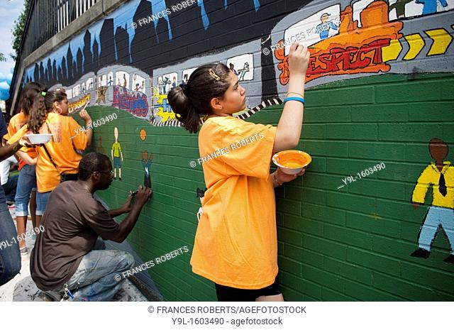 Volunteers and students paint a mural against bullying at a middle school in the Richmond Hill neighborhood in the borough of Queens in New York
