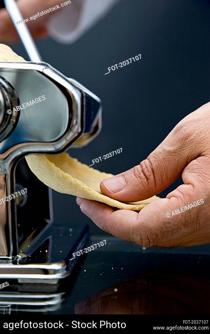 Close up of a hand holding pasta dough coming out of a pasta maker